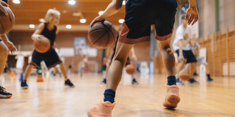 Junior level basketball player bouncing basketball. Young basketball player with classic ball. Basketball training session for youth. School sports class