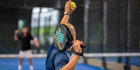 Monitor teaching padel class to man, his student - Trainer teaches boy how to play padel on indoor tennis court